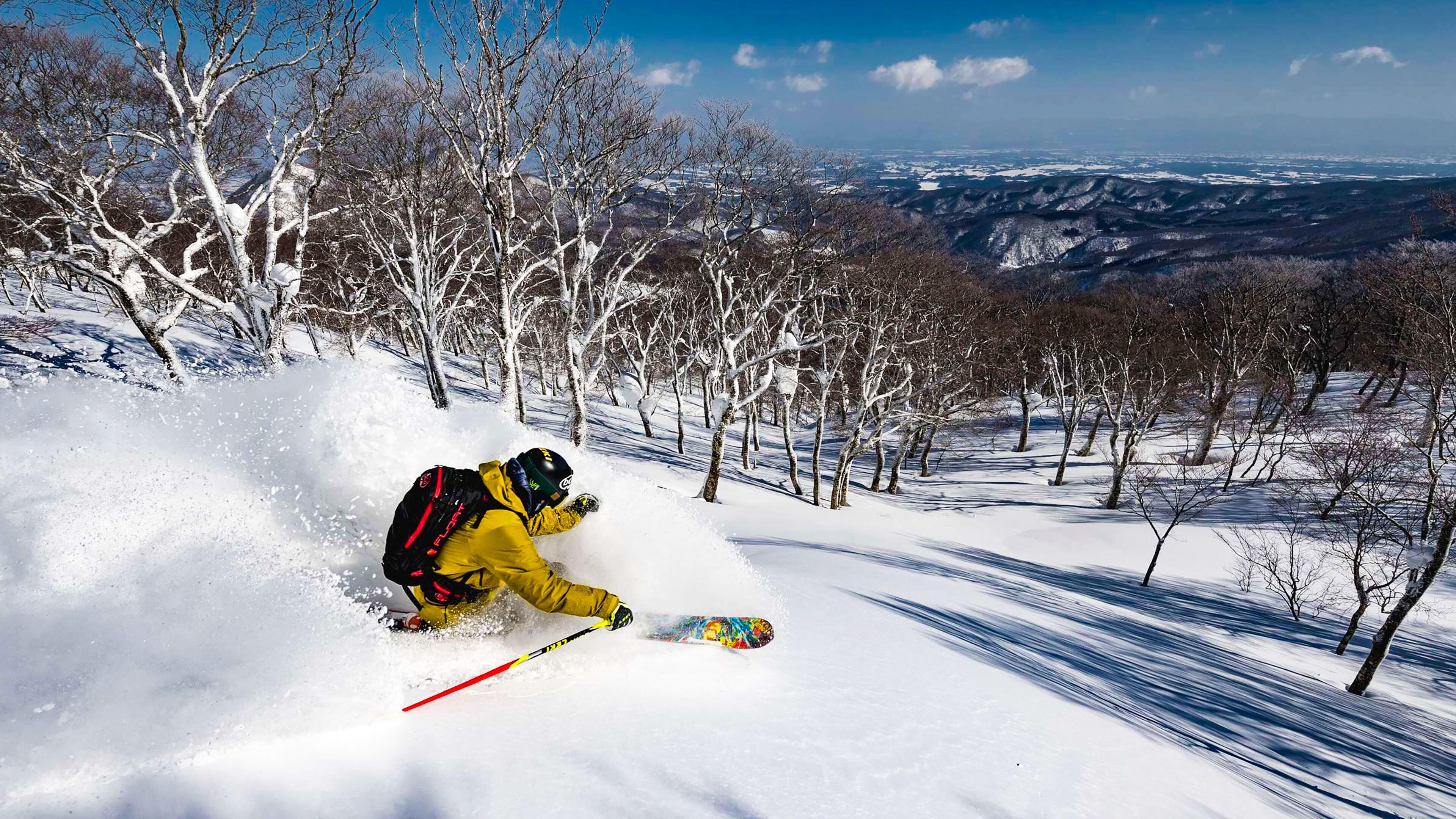 A snowy mountain slope with a skier in motion.