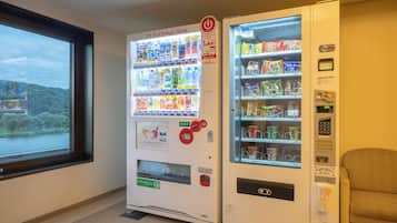 Two vending machines in a room with a window overlooking a natural landscape.