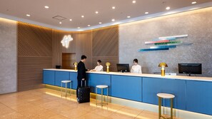 A reception area with a modern design, featuring a counter, three bar stools, and a television. - ANA Holiday Inn Iwate Kitakami by IHG (Kitakami)