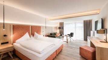 A modern hotel room with a large bed, a desk, a chair, and a sofa.