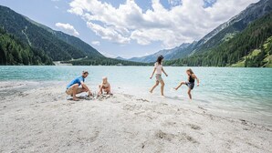 Un grupo de personas junto a un lago con montañas al fondo.
