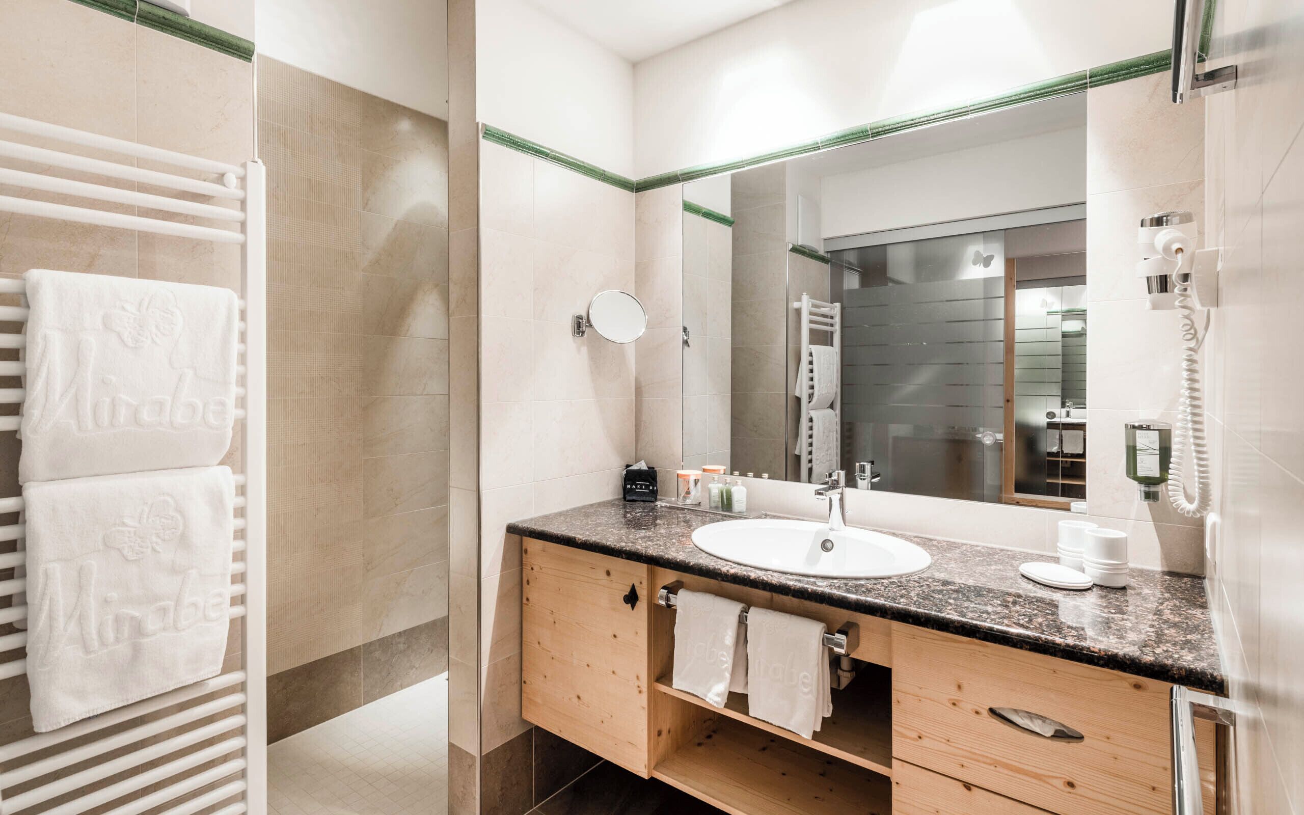 A modern bathroom with a sink, mirror, and towel rack.
