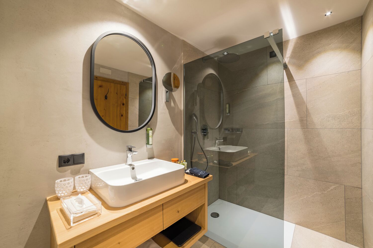 A modern bathroom with a large sink, mirror, and shower area.