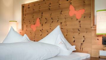 A hotel room with a wooden headboard, white bedding, and decorative butterfly cutouts.