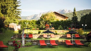 Un patio con mobiliario exterior, muros de piedra y montañas al fondo.