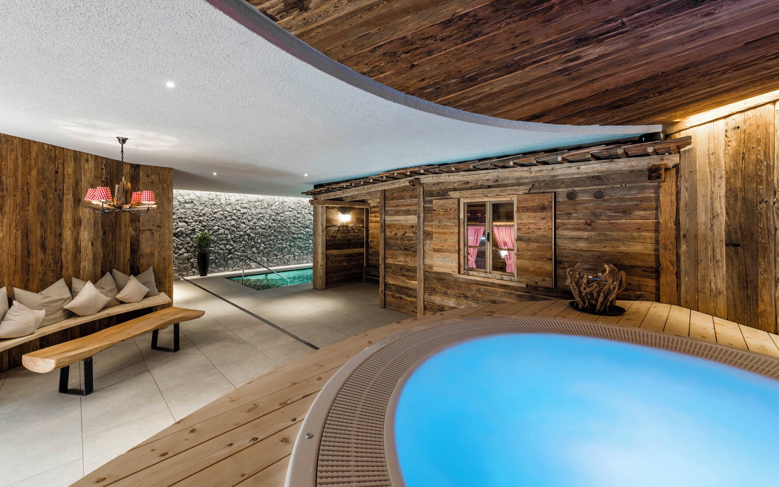 Eine Holzhütte mit Pool, Steinmauer und einer Bank.