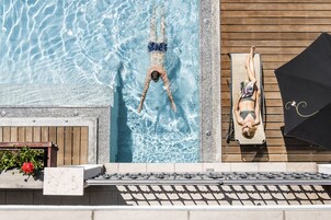 Una piscina techada, una piscina al aire libre, sombrillas