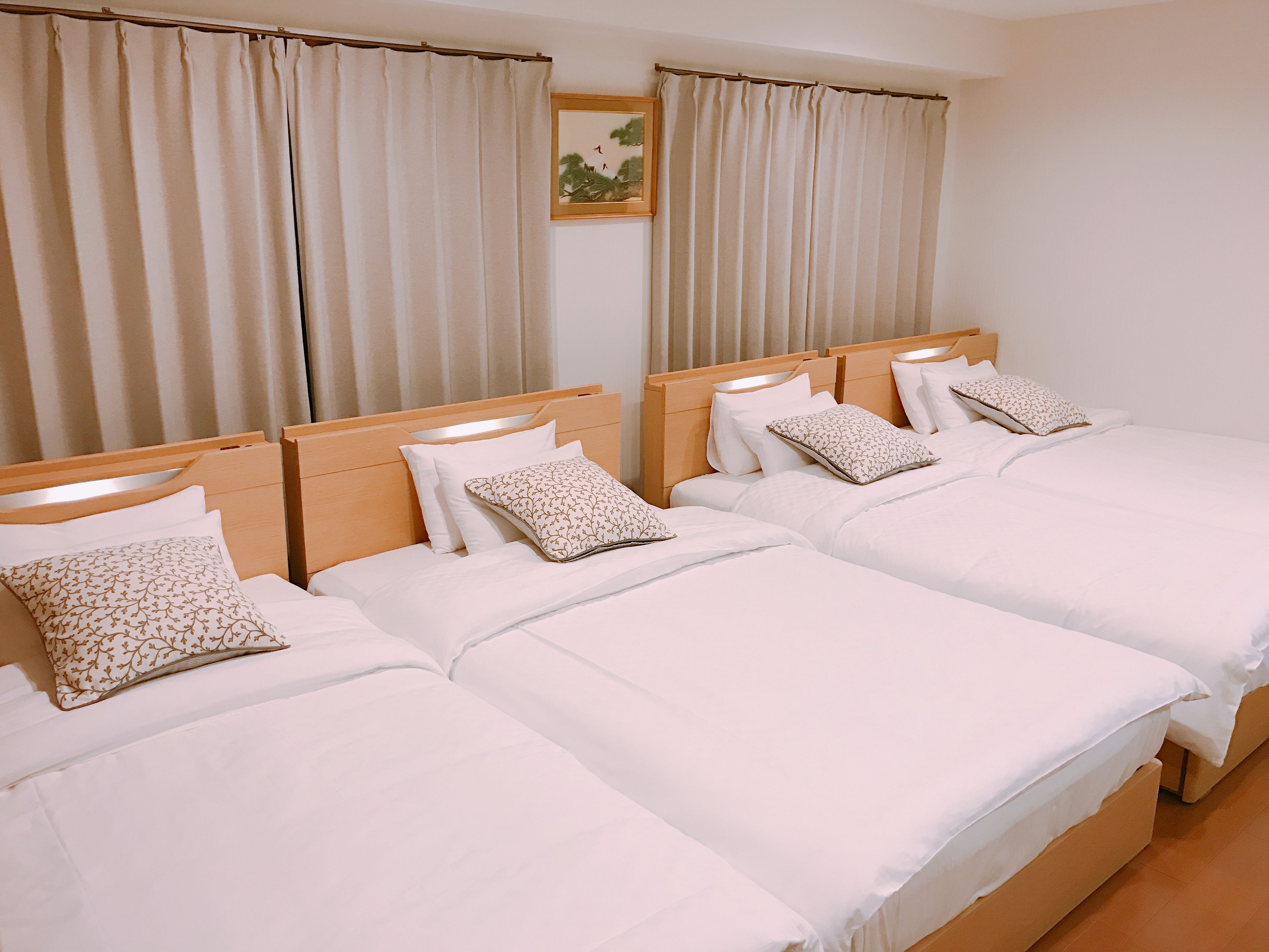 Habitación de hotel con dos camas, cada una con ropa blanca y almohadas estampadas.
