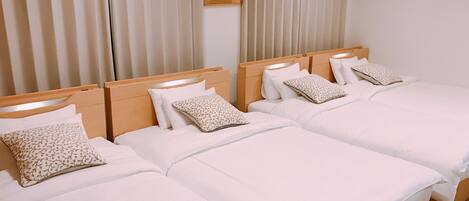 Habitación de hotel con dos camas, cada una con ropa blanca y almohadas estampadas.