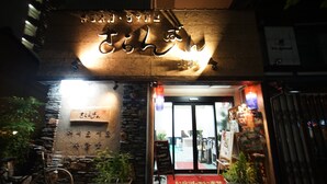 A restaurant entrance with a stone facade, a bicycle parked outside, and a red mat at the door. - Sarangbang (Kyoto)
