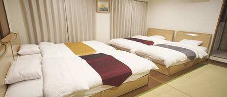 Habitación de hotel con dos camas, un ventanal con cortinas, un aire acondicionado instalado en la pared y un pequeño cuadro en la pared.
