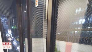 A corner of a hotel lobby with a glass partition, a fire extinguisher, a trash bin, and a small potted plant. - Sarangbang (Kyoto)