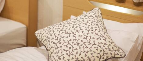 A hotel room with a bed, a pillow, a headboard, a painting on the wall, and curtains.