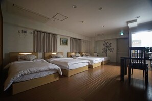 A hotel room with three beds, wooden flooring, and a dining area with a table and chairs. - Sarangbang (Kyoto)