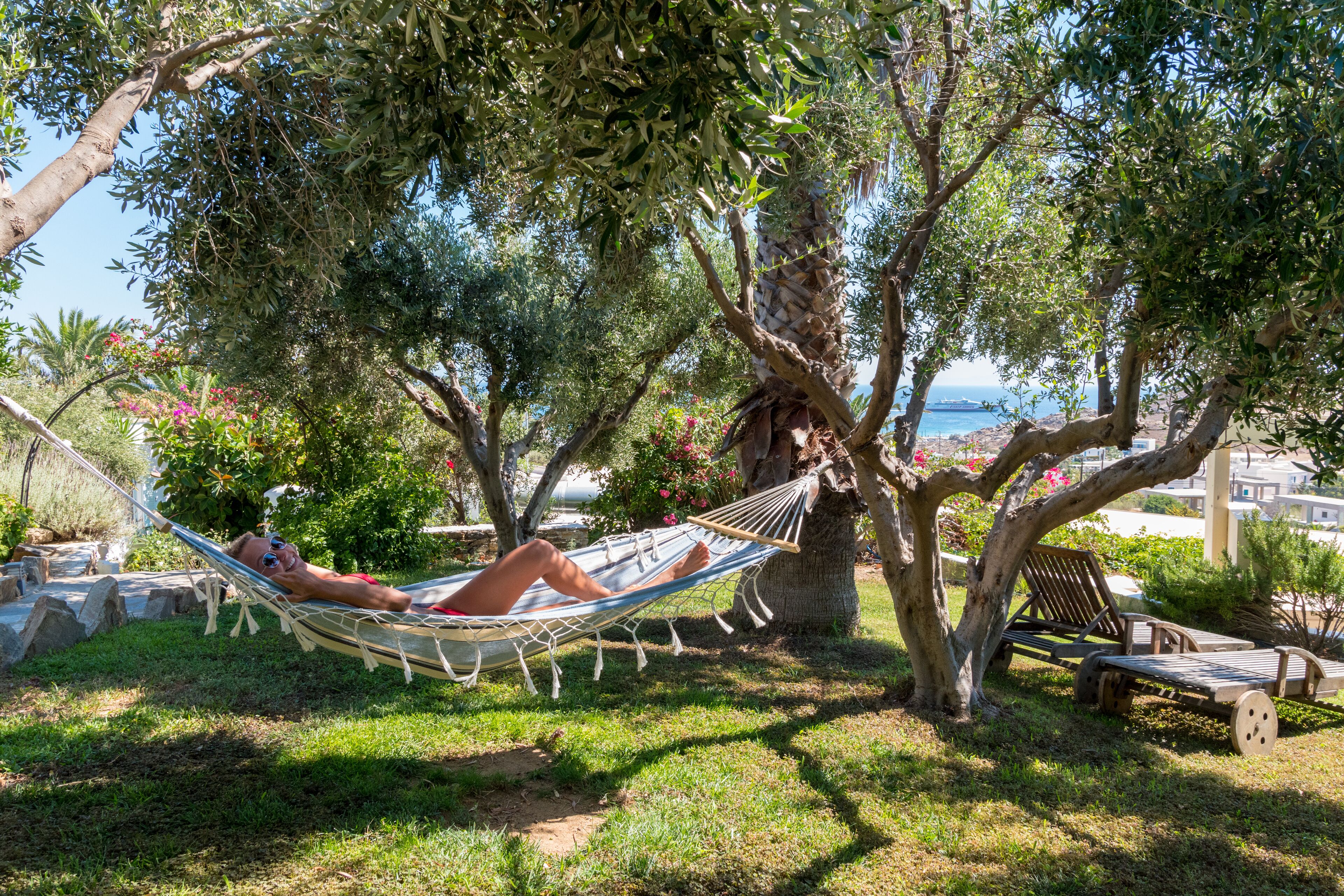 Un hamac sous un arbre, un banc en bois et une vue sur la mer.