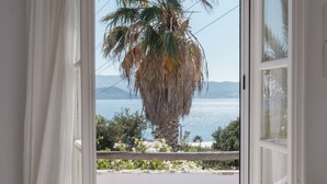 Un balcón abierto con vista al mar y palmeras.