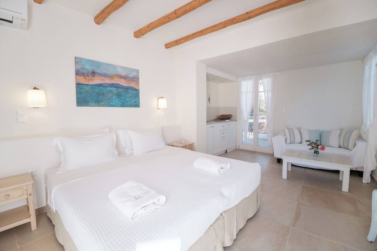 Habitación de hotel con una cama grande, un sofá, un cuadro en la pared y vistas al exterior.