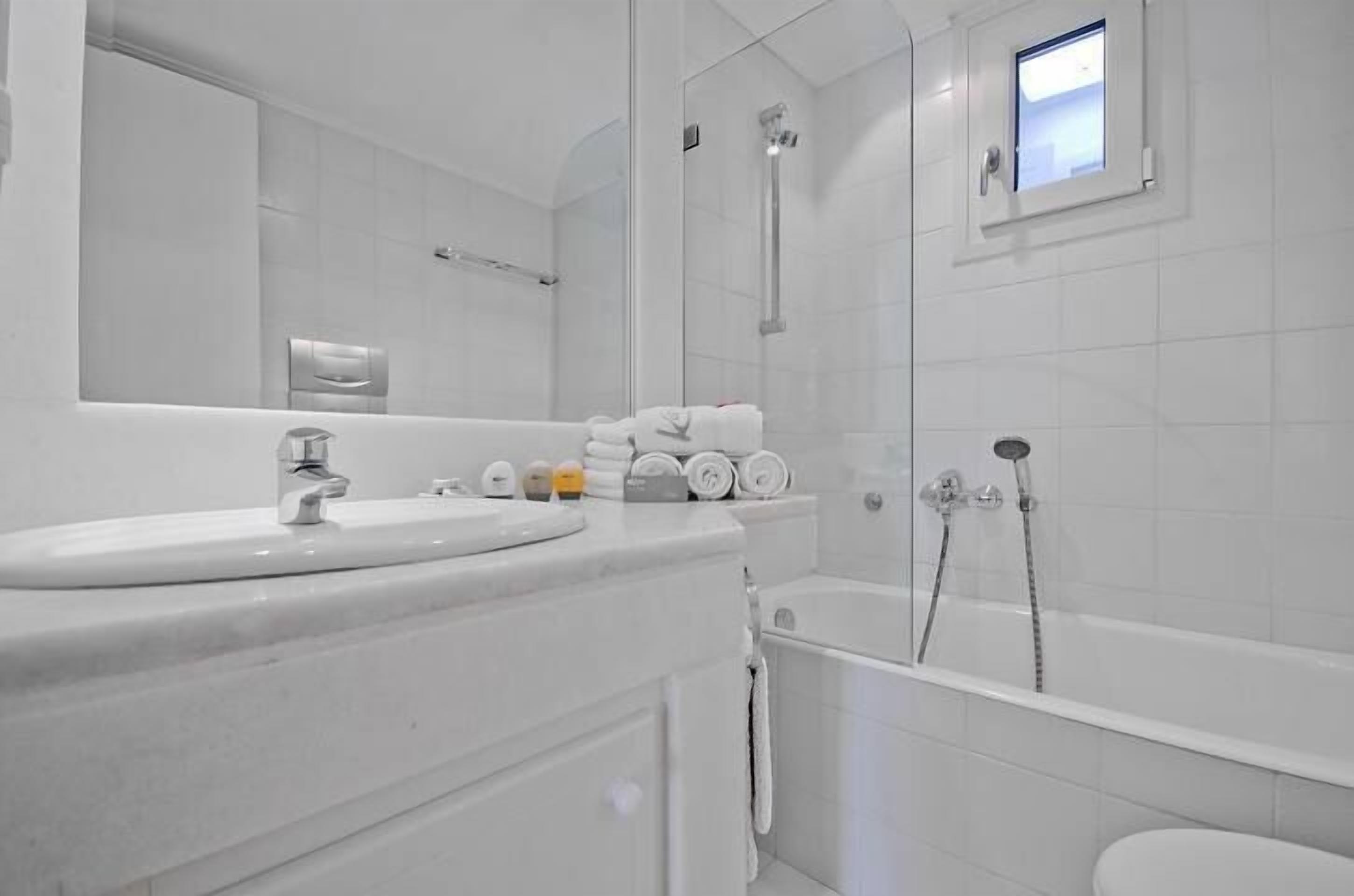 A modern bathroom with a white sink, a mirror, a glass-enclosed shower, and a toilet.