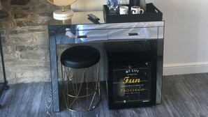 A room with a television mounted on the wall, a small bar area with stools, a coffee machine, and a decorative sign. - Windy Bank Hall - Holiday Home (Sheffield)