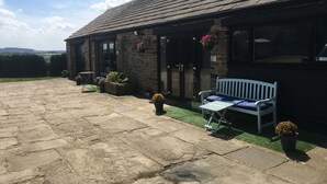 A stone patio with a bench and potted plants. - Windy Bank Hall - Holiday Home (Sheffield)
