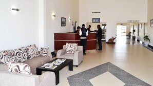 Et hotellobby med reception, sofaer, et sofabord og en stribet måtte.