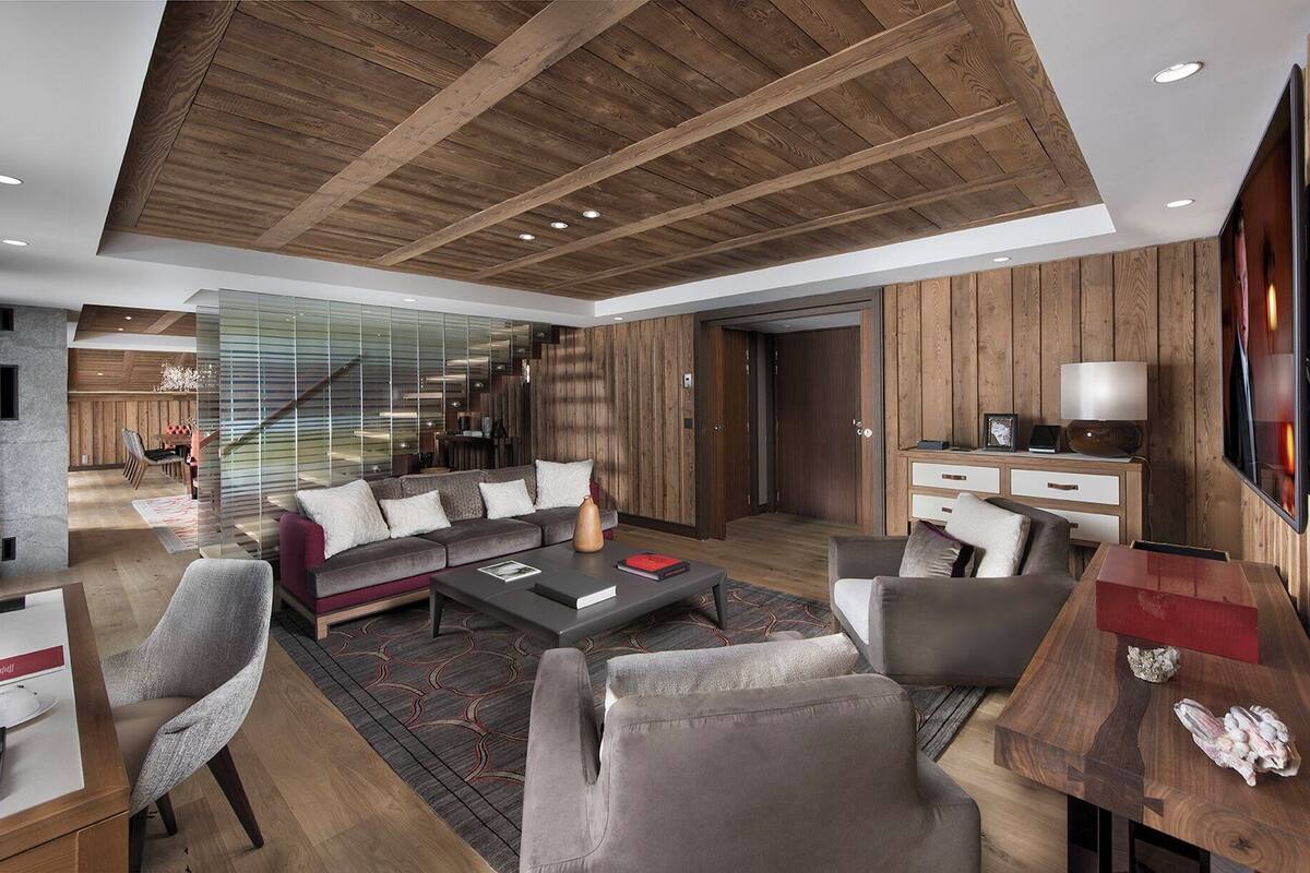Una sala de estar moderna con techo de madera, un conjunto de sofá, una mesa de centro y un televisor.