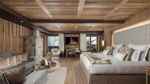 A modern hotel room with a wooden ceiling, a large bed, a sofa, a desk, and a view of the outdoors.