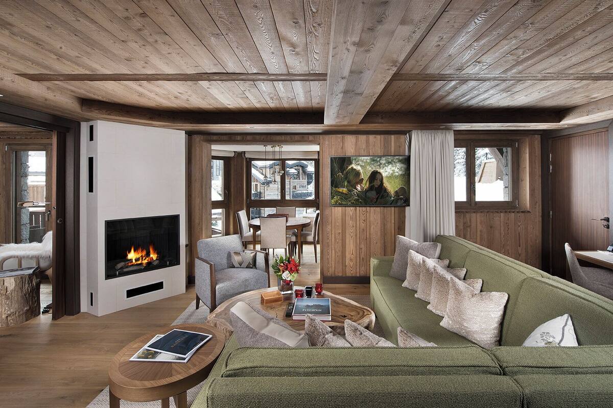 Una sala de estar moderna con chimenea, techo de madera y ventanas amplias.