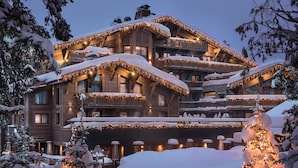 A multi-story wooden lodge with balconies, snow-covered trees, and string lights.