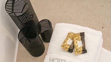 A white towel with "HOTEL SPIROS" printed on it, black cylindrical objects, and green foliage.