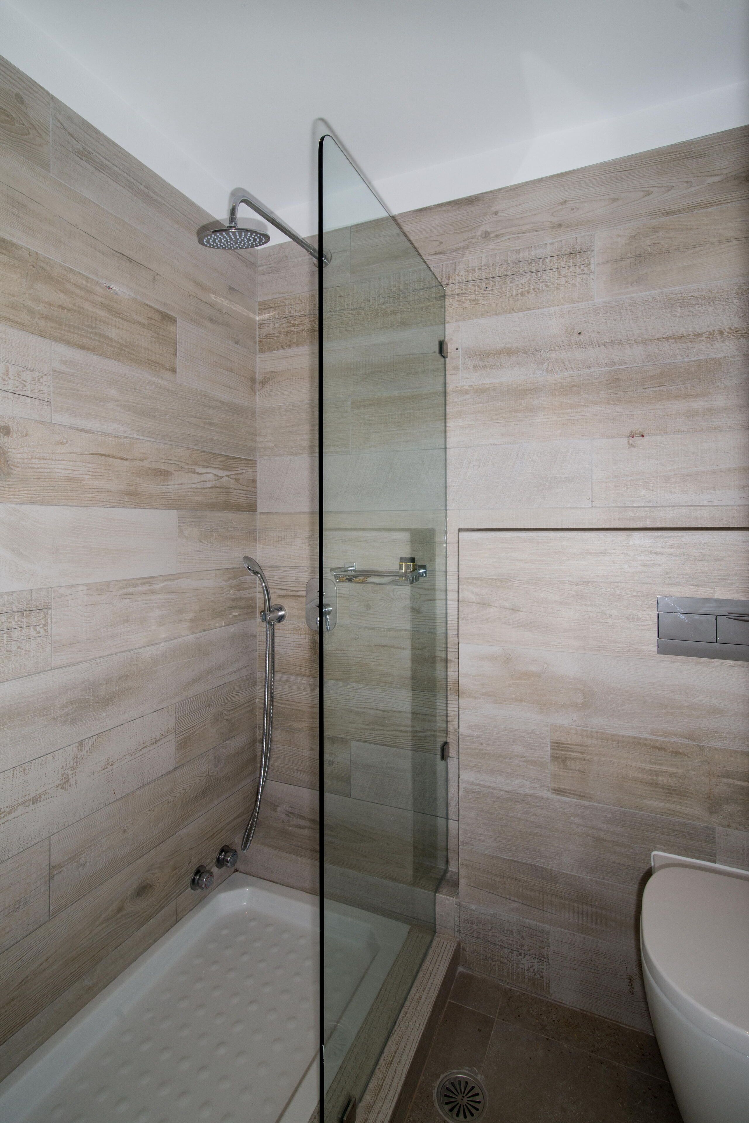Un baño moderno con cabina de ducha de vidrio, bañera y retrete.