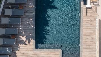 An aerial view of a swimming pool area with lounge chairs and a deck.