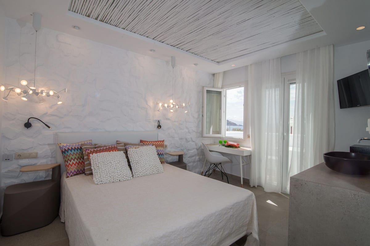 Une chambre à coucher moderne avec un lit, des tables de chevet, un bureau et un téléviseur.