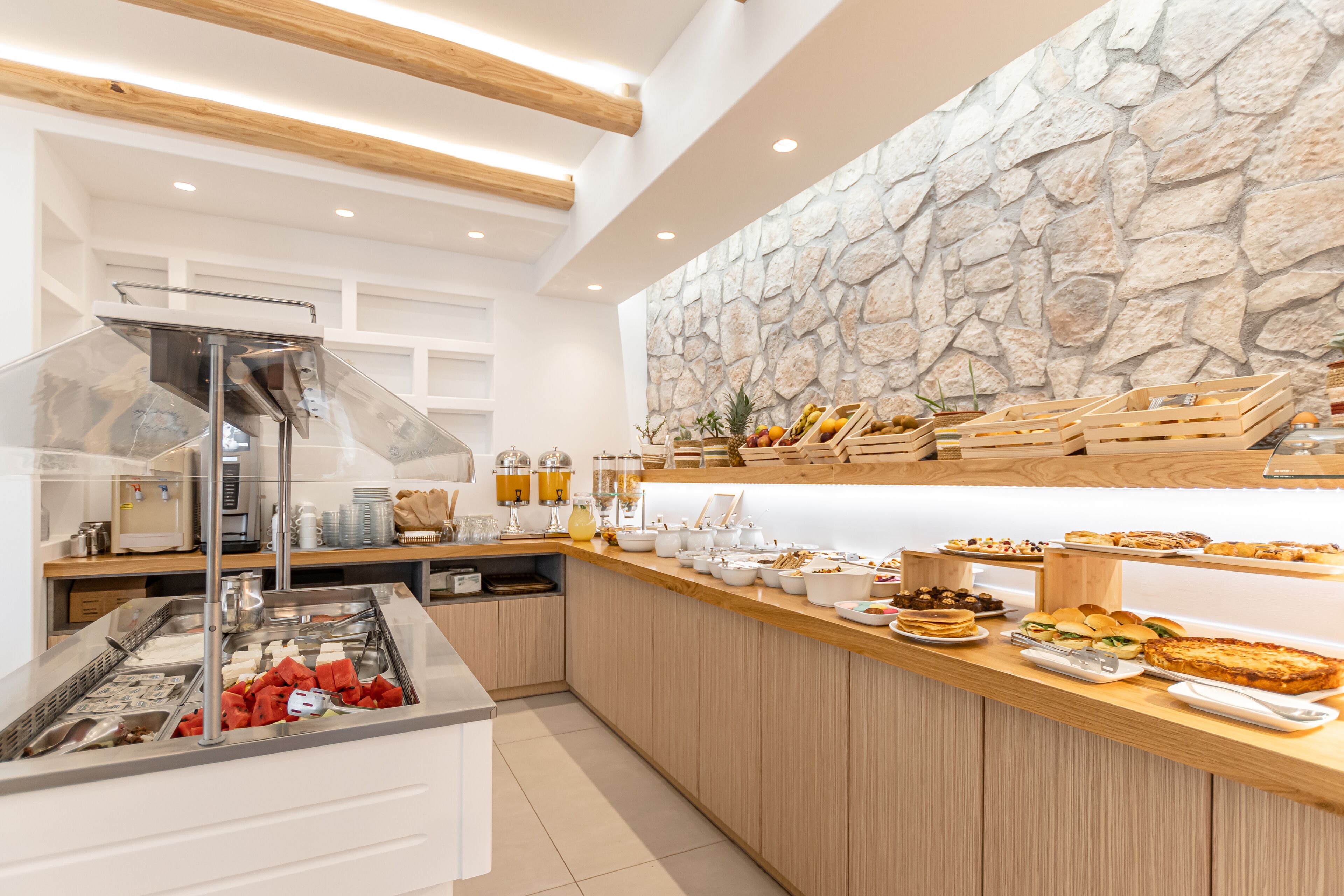 A buffet area with a stone wall, wooden counter, and various food items.