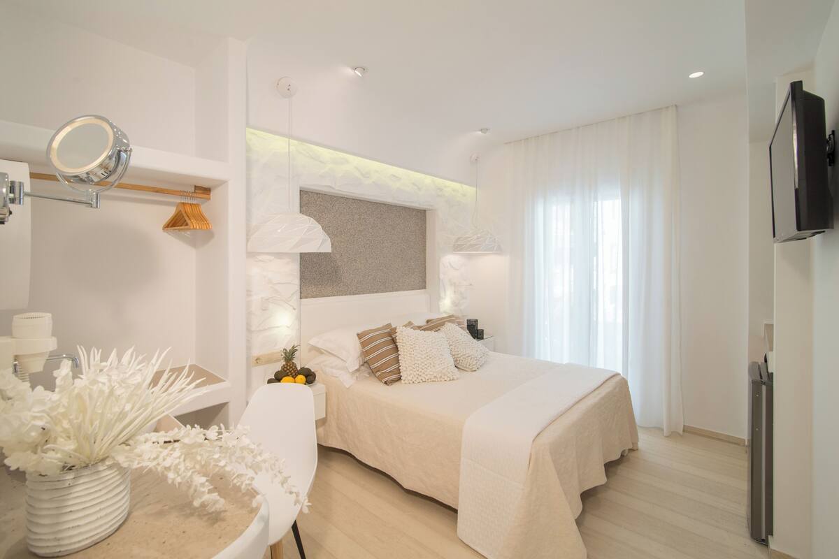 Une chambre moderne avec un grand lit, des tables de chevet, un miroir et un téléviseur.