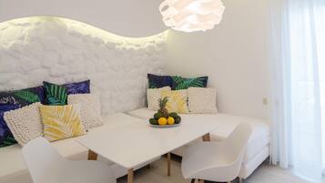 A modern living room with a white sofa, a dining table, and a unique ceiling design.