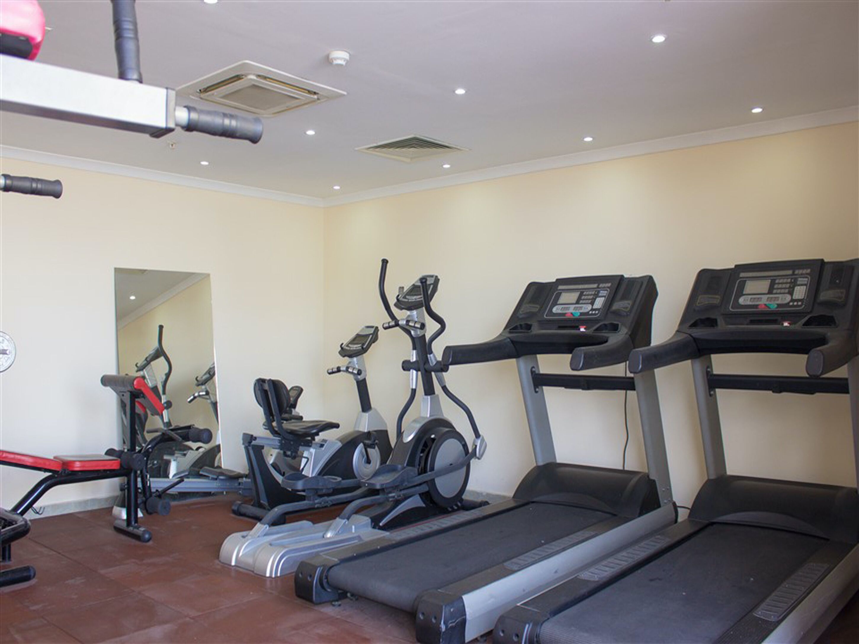 Une salle de sport équipée de tapis de course, de vélos elliptiques et d’un banc de musculation.