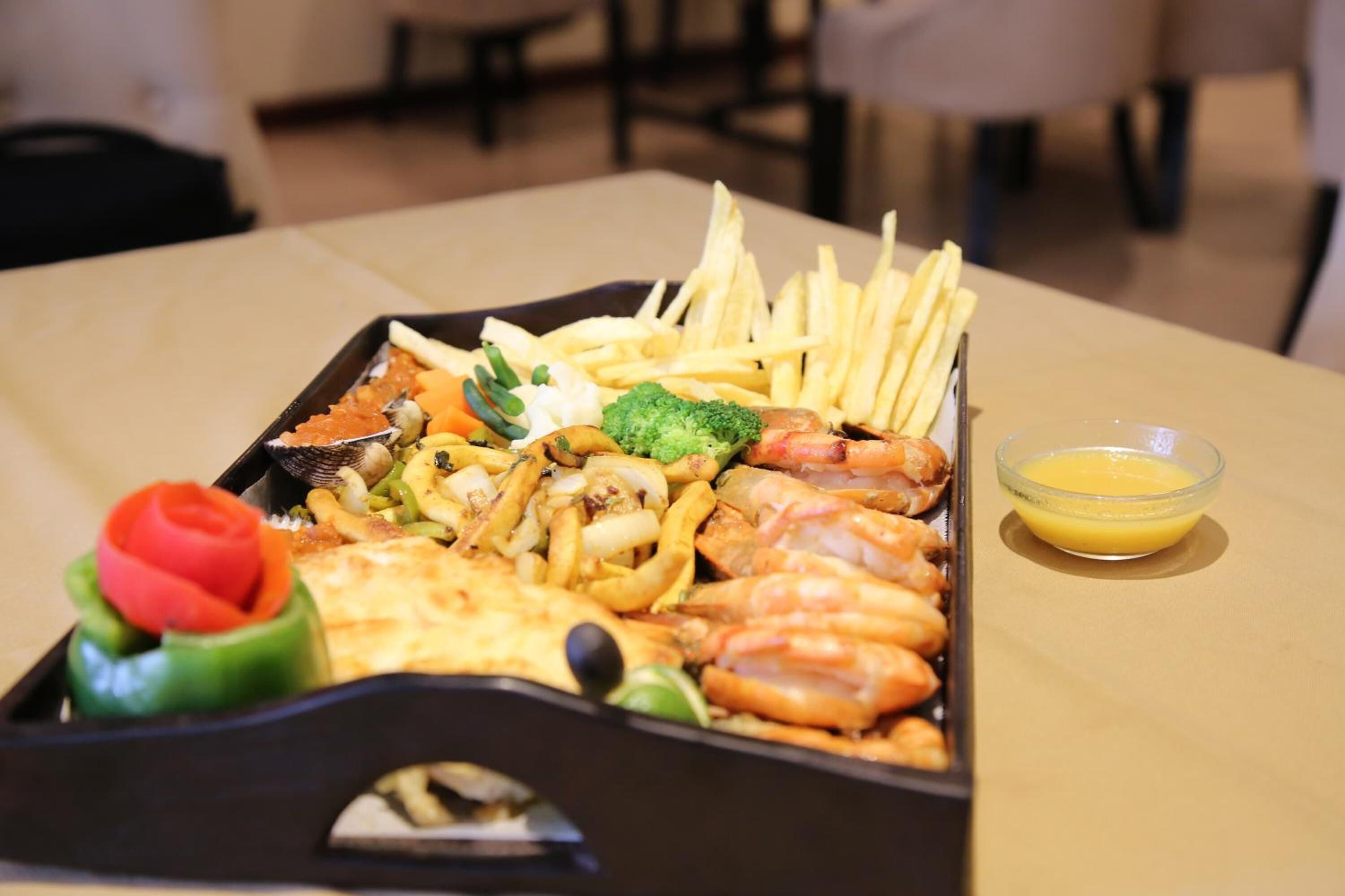A tray of food including shrimp, fries, and vegetables on a table.