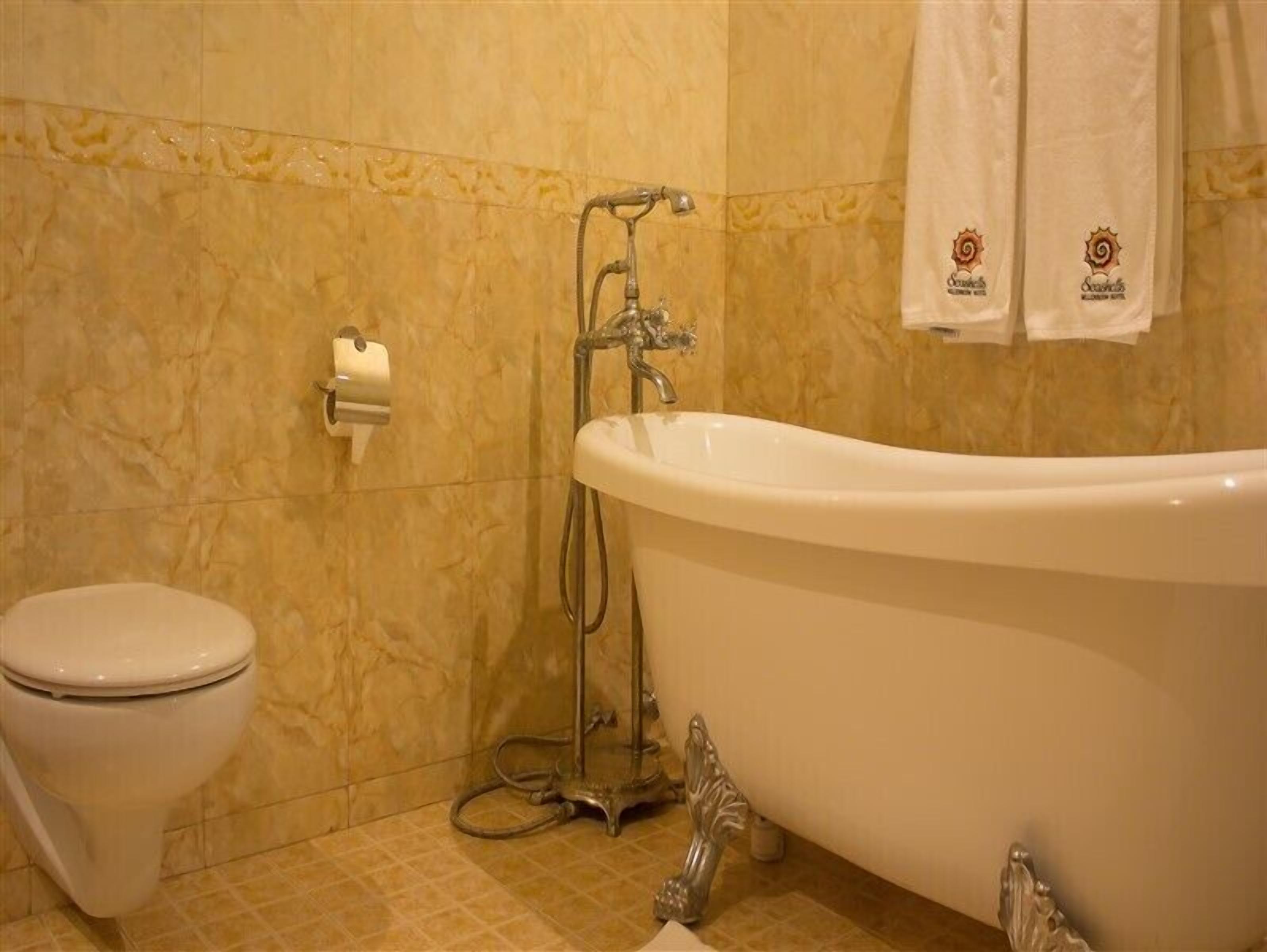 A bathroom with a bathtub, toilet, and a towel rack with towels.