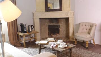 A living room with a fireplace, a coffee table with cups and saucers, a chair, and a lamp.