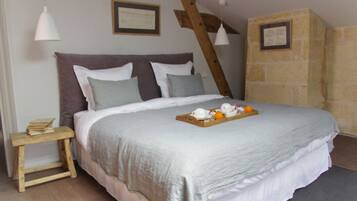A bedroom with a bed, a wooden headboard, a nightstand, and a tray with oranges and a teapot.