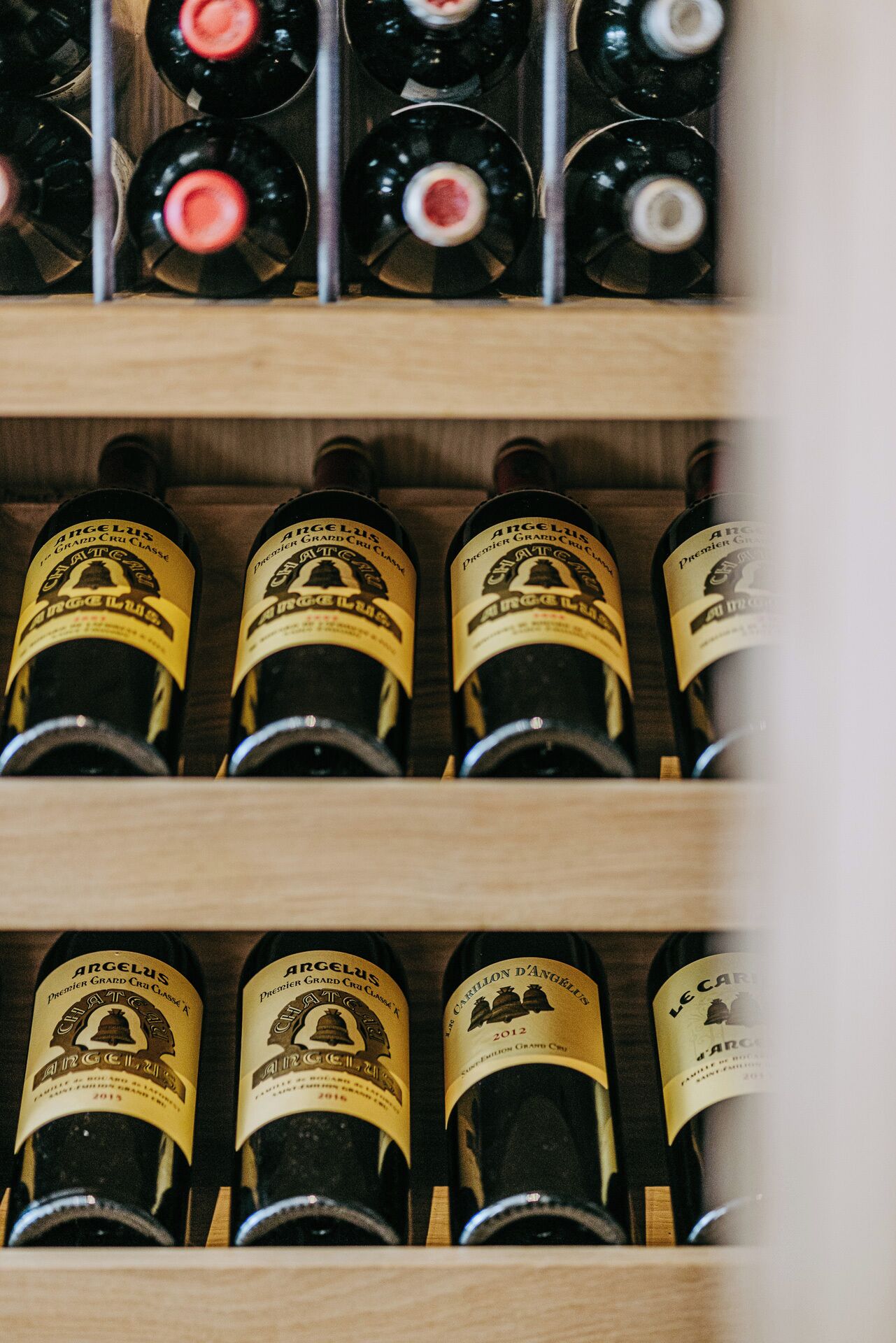 Uma estante de madeira com garrafas de vinho Angelus.