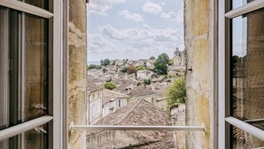Vista desde una ventana abierta a un pueblo histórico con edificios de piedra y una torre destacada.