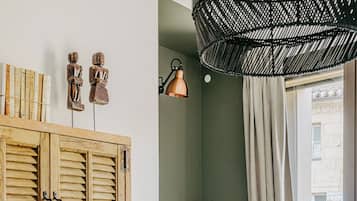 A room with a wooden desk, a wicker chair, a hanging light fixture, and a window with curtains.