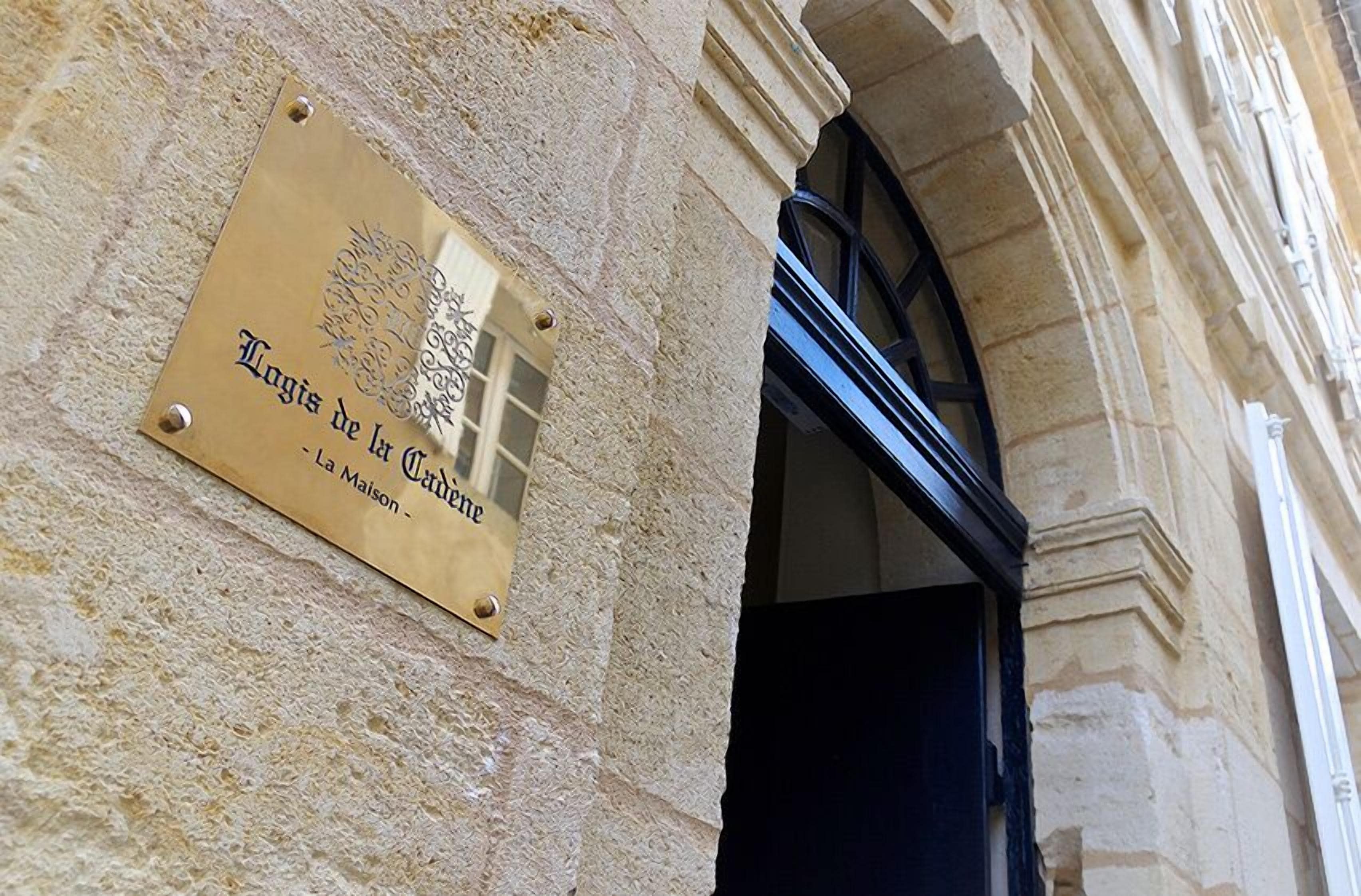 A plaque on a building wall with text and a logo.