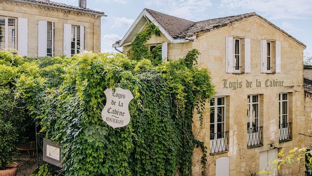 Un edificio con una señal que dice “Logis de la Cadène RESTAURANT”, parcialmente cubierto de hiedra.