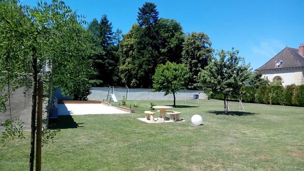 A backyard with a swimming pool, picnic table, and a swing set.