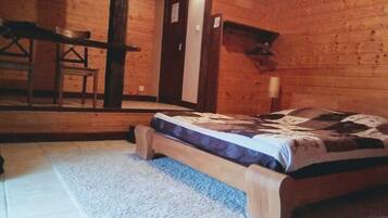 A wooden cabin bedroom with a bed, a small table, and a chair.