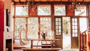 Un interior rústico con un banco de madera, una silla de mimbre y una chimenea.