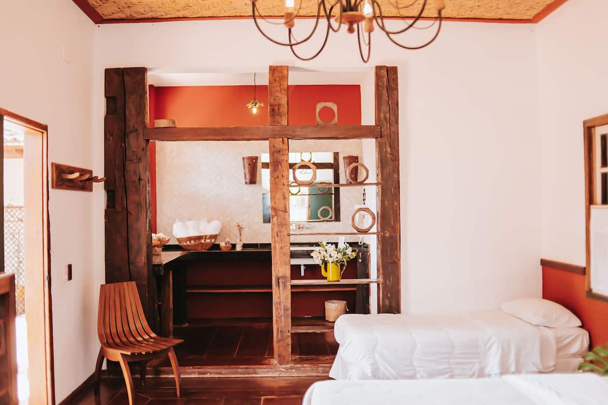 Um quarto com uma cadeira de madeira, uma cama e uma estante com objetos decorativos.